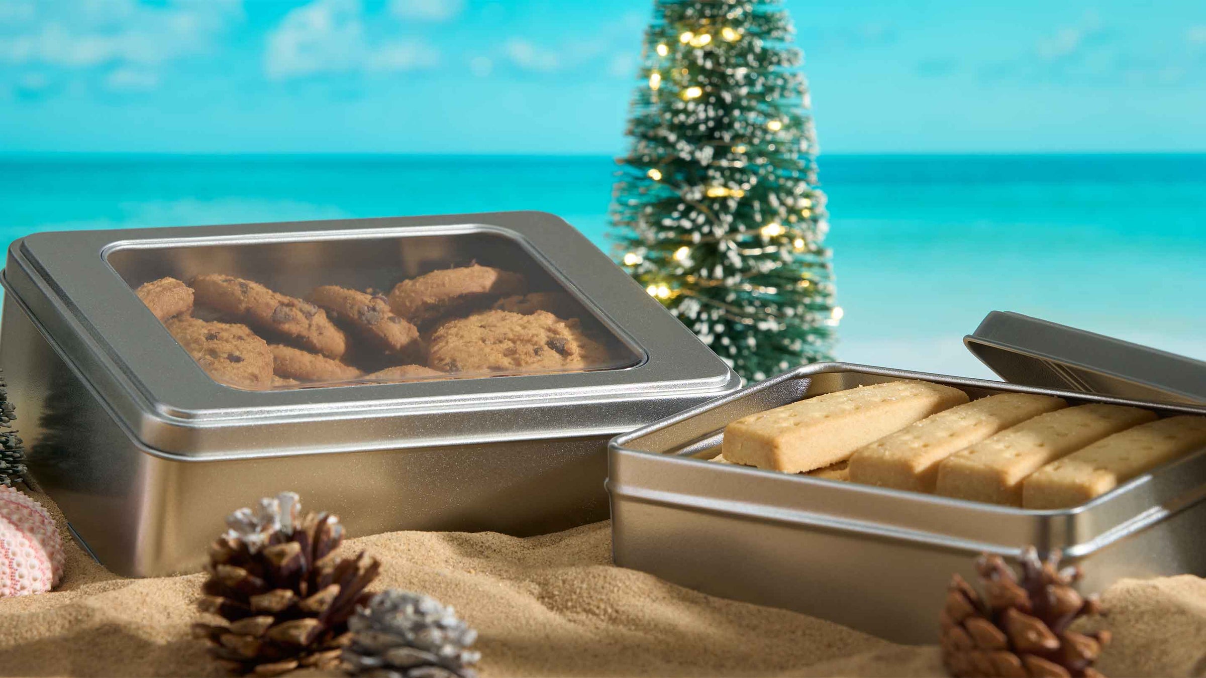 Biscuit tin packaging on beach with Christmas decorations